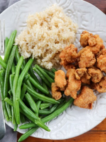 Trader Joe's Mandarin Chicken with green beans and rice on a white pottery plate.