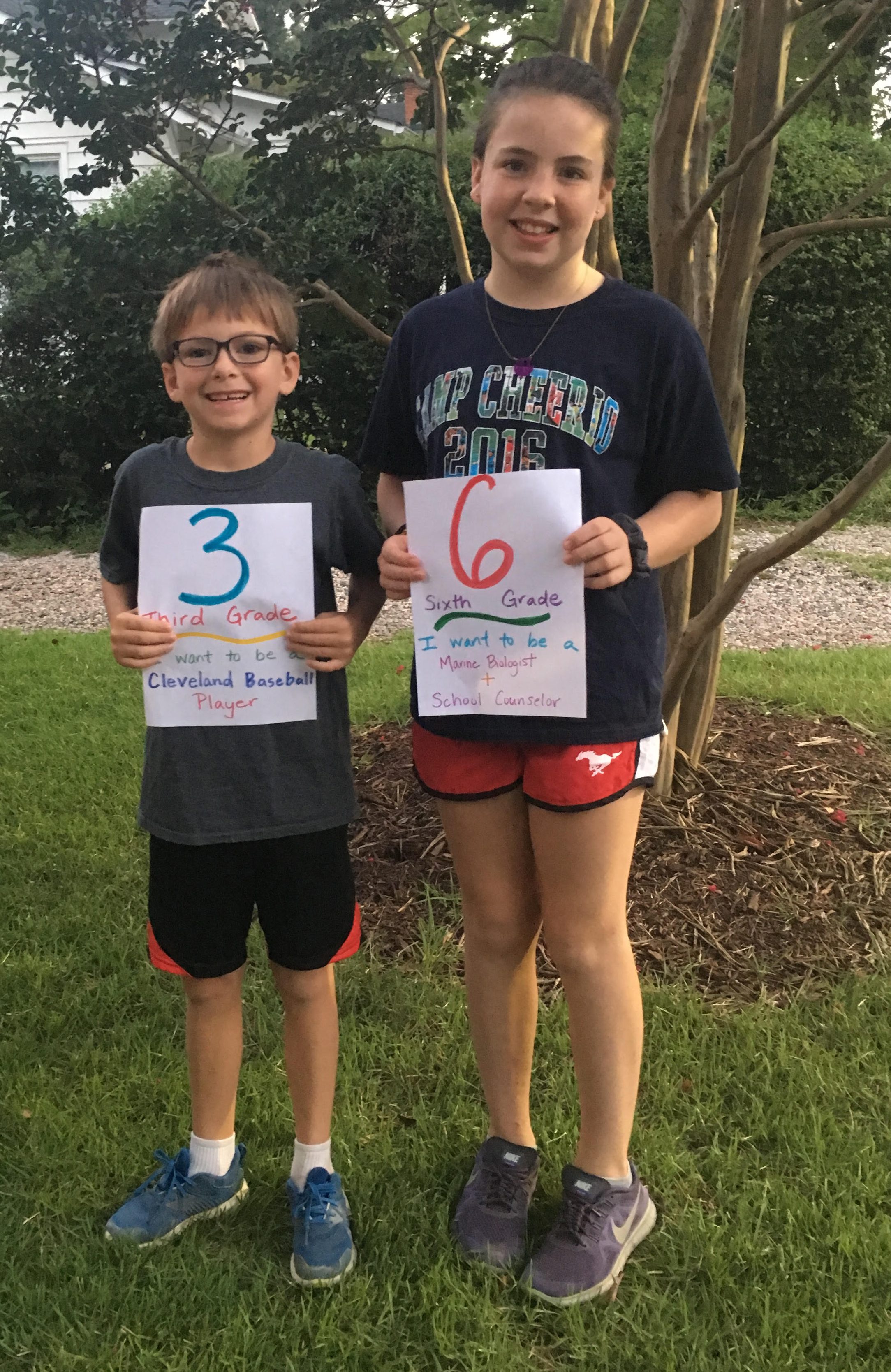 Two children holding first day of school signs. One going into 3rd grad and one going into 6th grade.