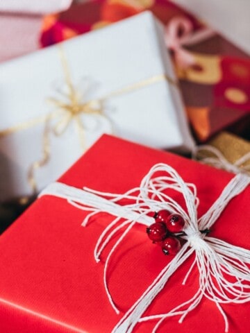 A gift wrapped in red paper and tied with sliver string in the foreground.