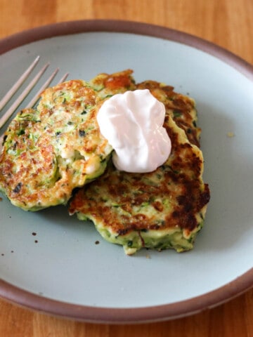 Three zucchini fritters topped with sour cream and served on an East Fork side plate in Malibu.
