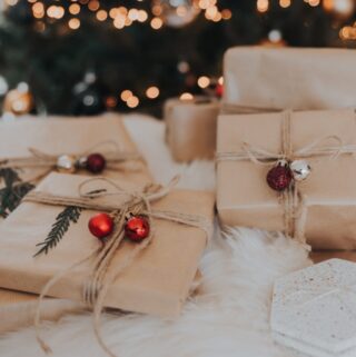 Christmas gifts wrapped in brown paper and tied with twine and decorated with small christmas decorations.