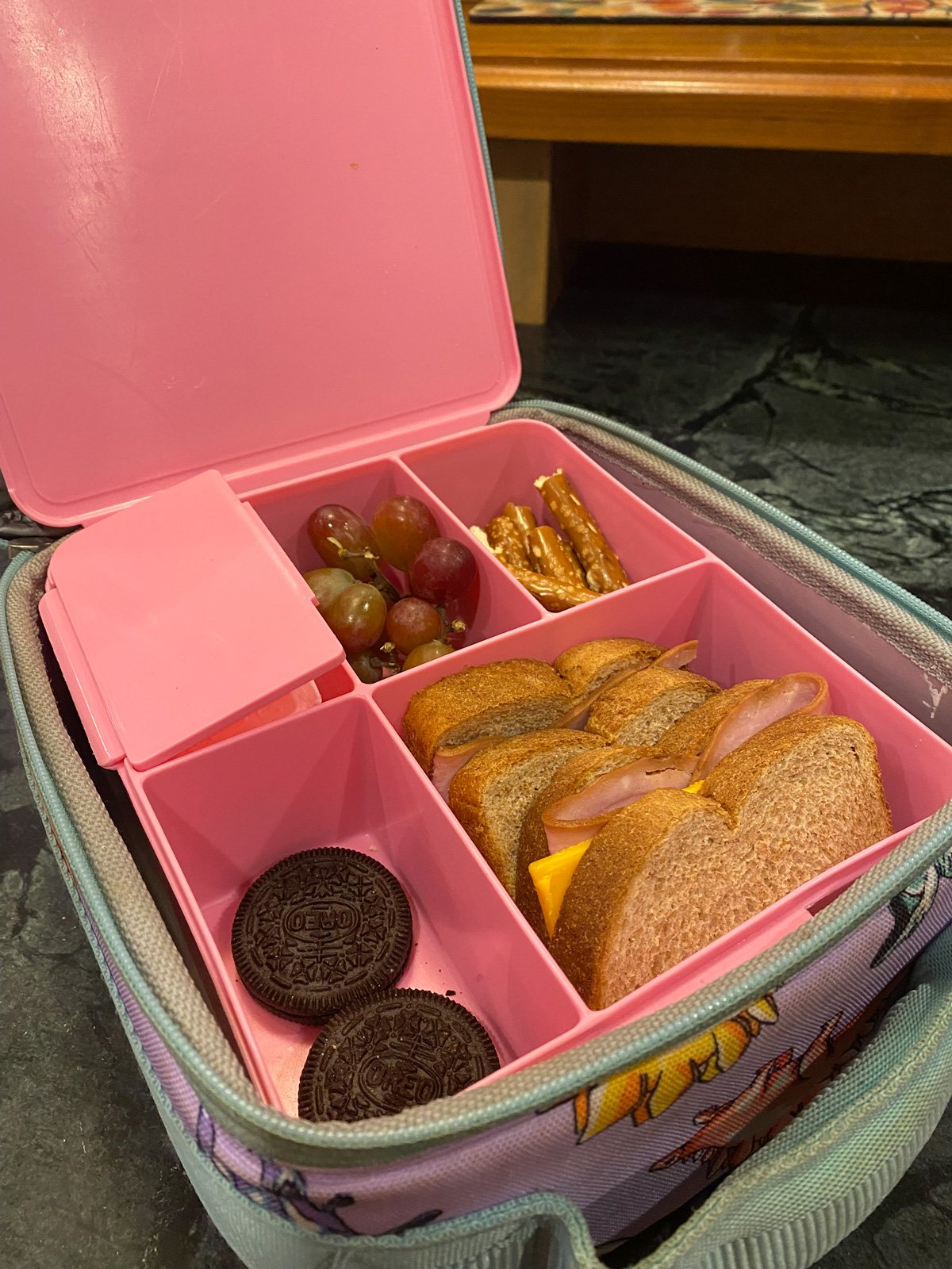Pottery Barn Bento lunch box with a sandwich, Oreo cookies, pretzels and grapes.