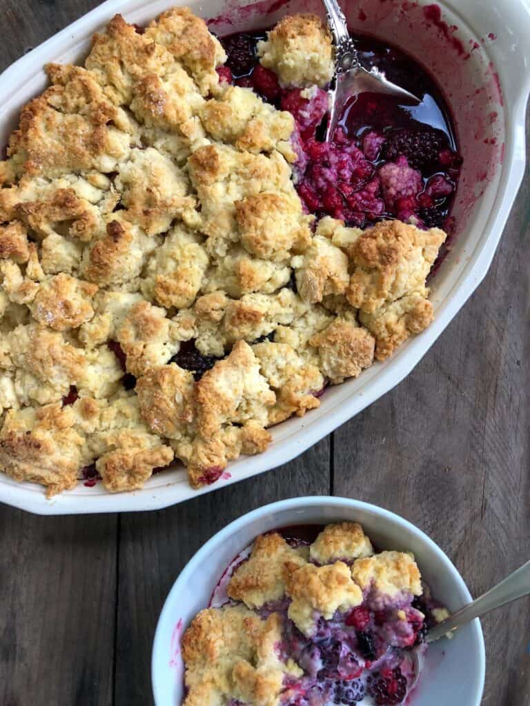 Mixed berry cobbler with biscuit topping in an oval dish.