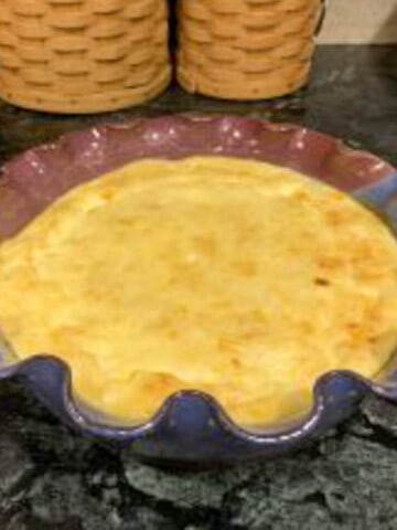 Baked corn pudding in a round pottery dish with fluted edges.