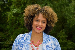 Dr. Lisa Folden, a black woman with curly brown hair and a blue a white jacket, looks at the camera and smiles. 