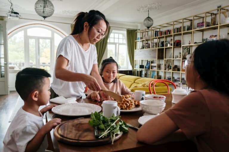 Family in the kitchen around a countertop while mom gets a meal together.