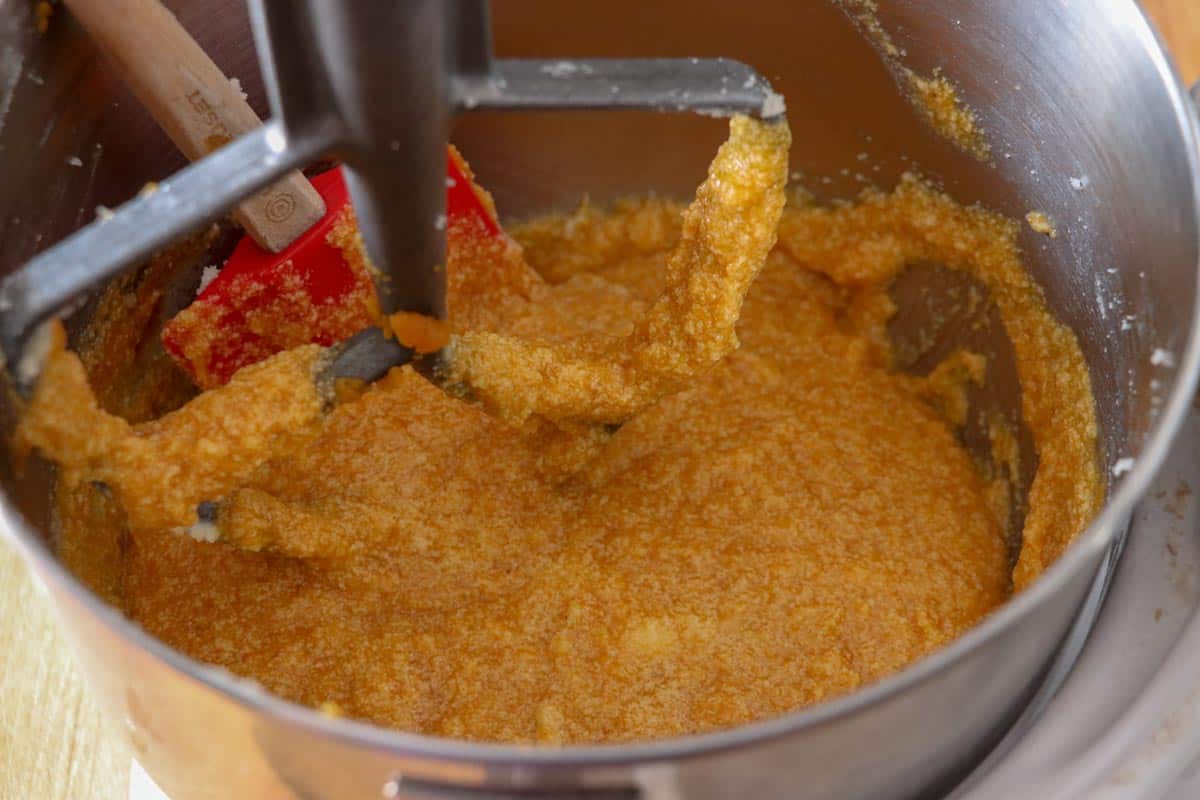 Pumpkin puree mixed into butter, sugar, egg mixture in the bowl of a Kitchen Aid Stand mixer. 