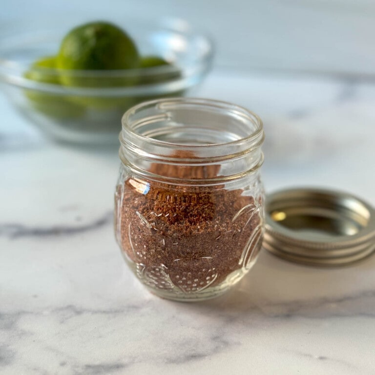 Homemade Mild Taco Seasoning in a glass jar on a marble countertop.