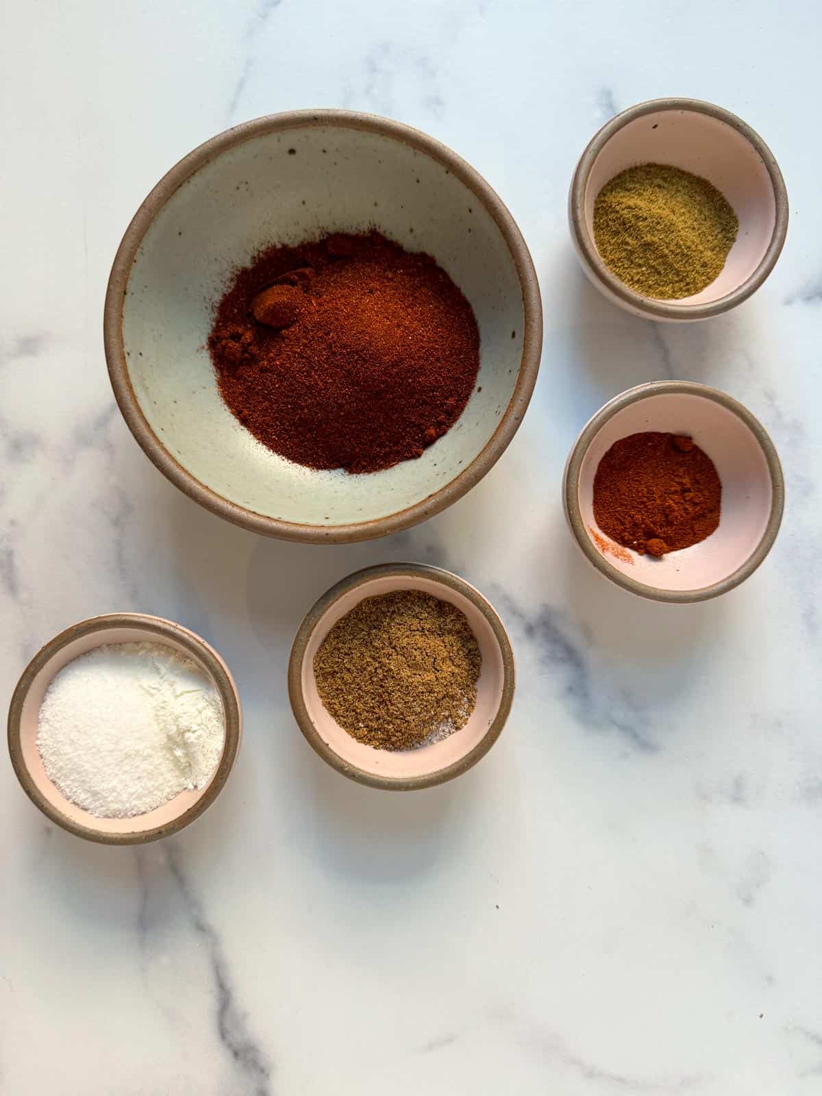 Homemade Mild Taco Seasoning Ingredients in small bowls on a marble countertop.
