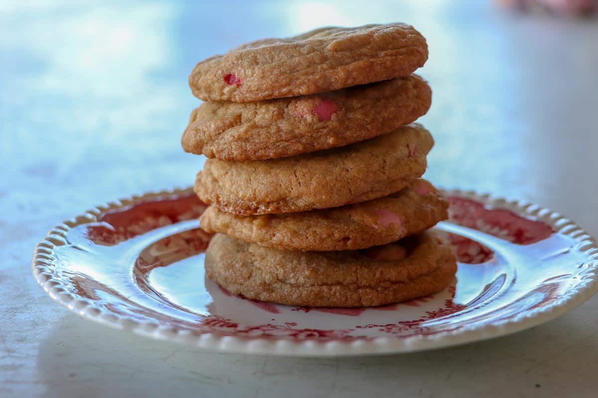 Five Valentines M&M cookies stacked on a red and white china plate.