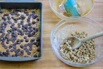 Melted caramels and chocolate chips over the first layer of baked oats, flour, brown sugar for Carmelitas.