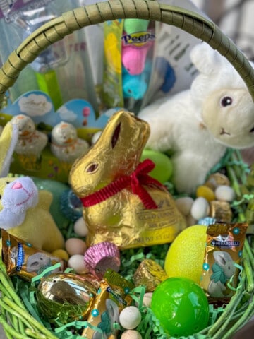 Easter basket filled with Easter basket ideas for kids like small stuffed bunny and stuffed lamb plus candy.