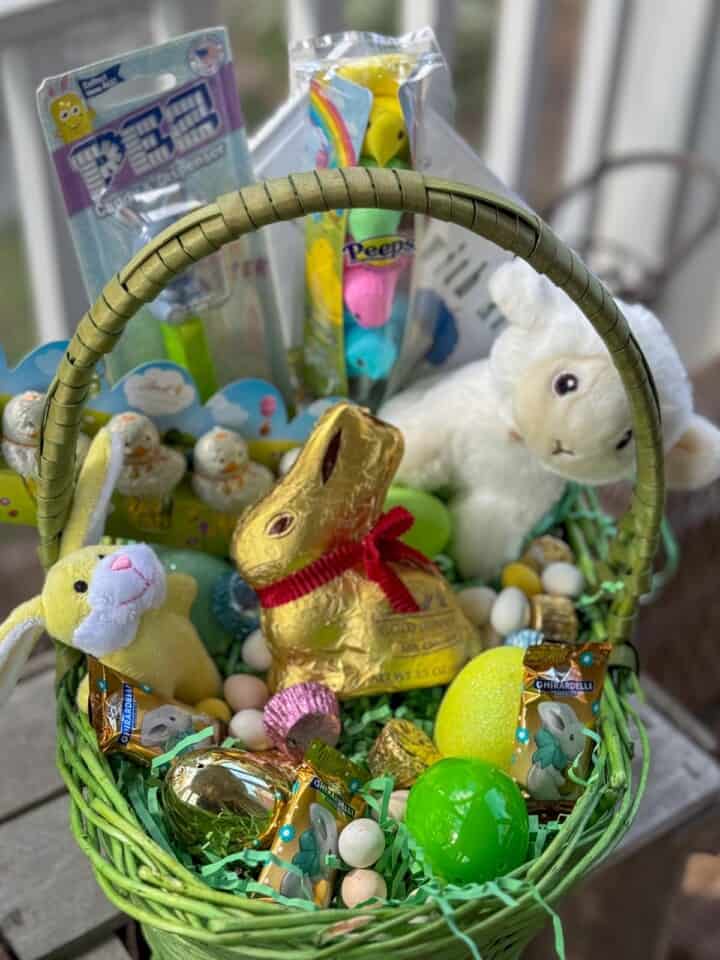 Easter basket filled with Easter basket ideas for kids like small stuffed bunny and stuffed lamb plus candy.